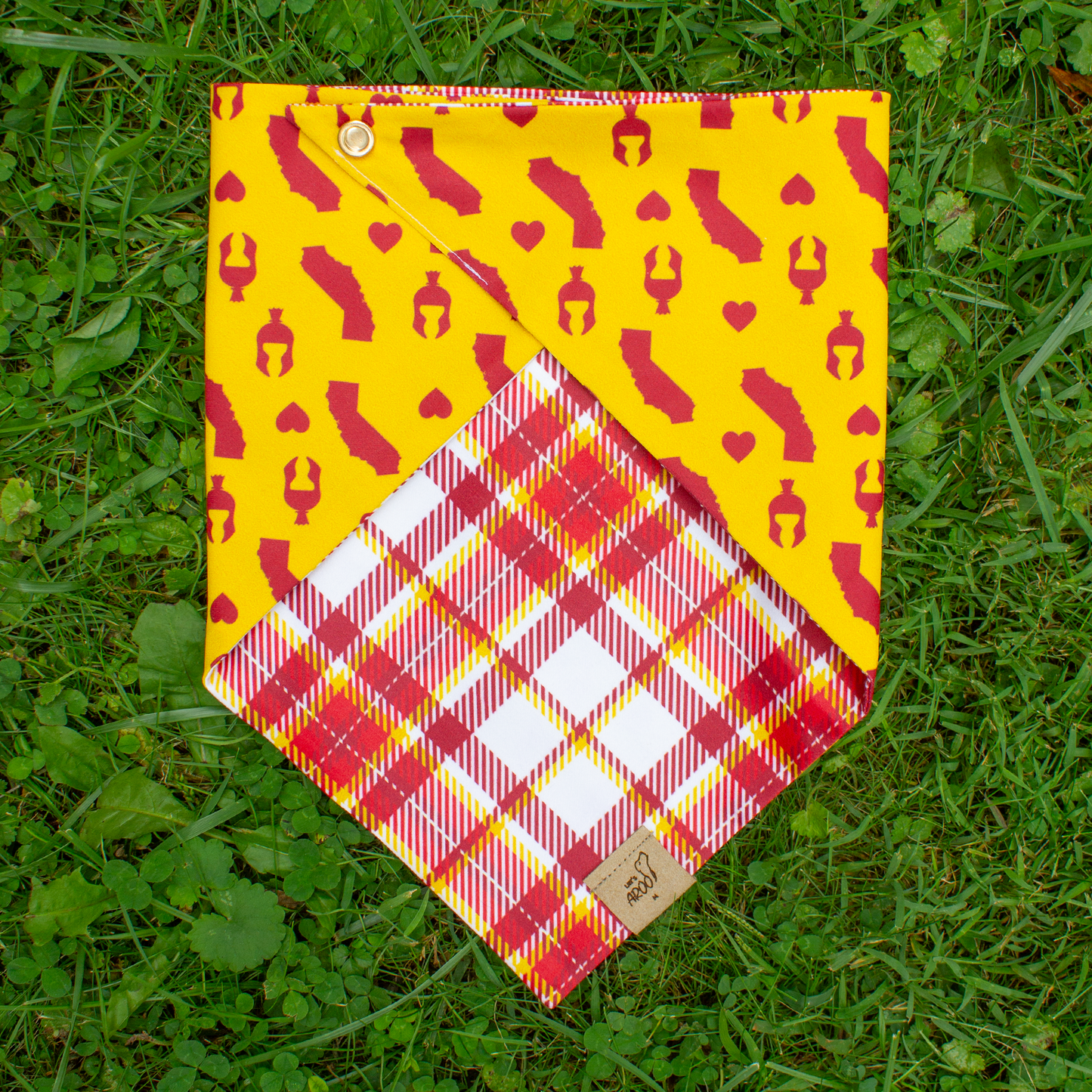 Dog bandana with yellow and red pattern on grass